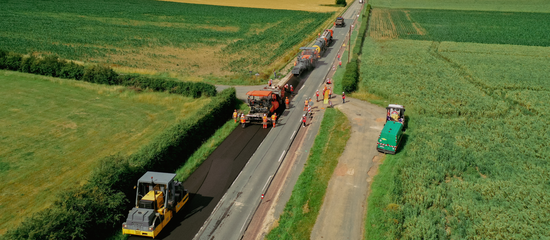 Colas crews place a new layer of asphalt onto a road. 