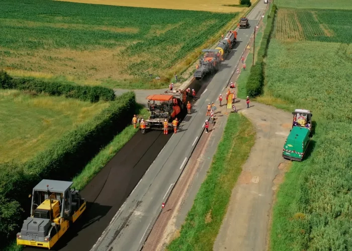 Colas crews place a new layer of asphalt onto a road. 
