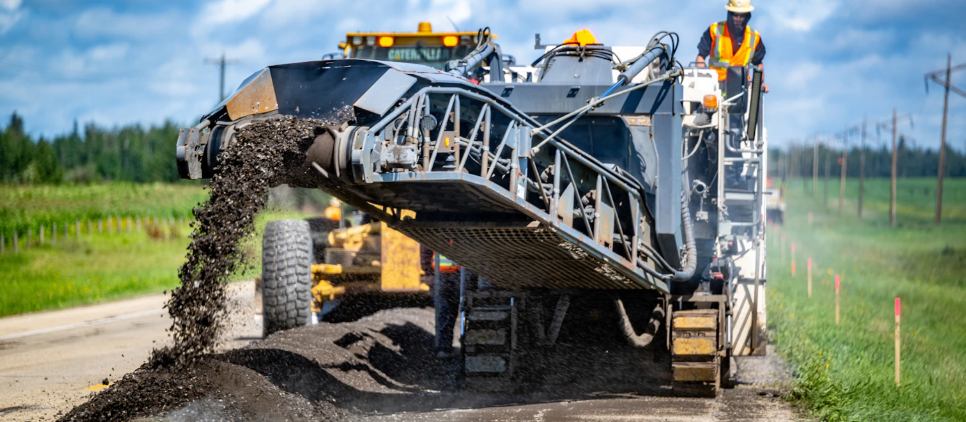 A machine from The Miller Group pours recycled material onto a roadway. 