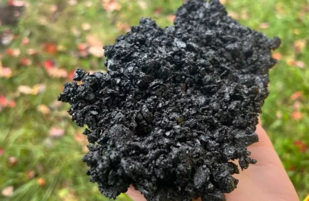 A Colas team member holds a handful of asphalt made from recycled plastic compounds.  