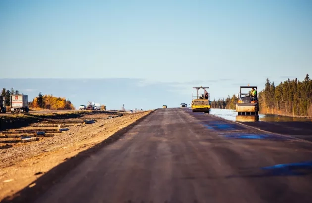 Paving crew completing work on the Highway 33 project with scenic blue sky and forest in the background.