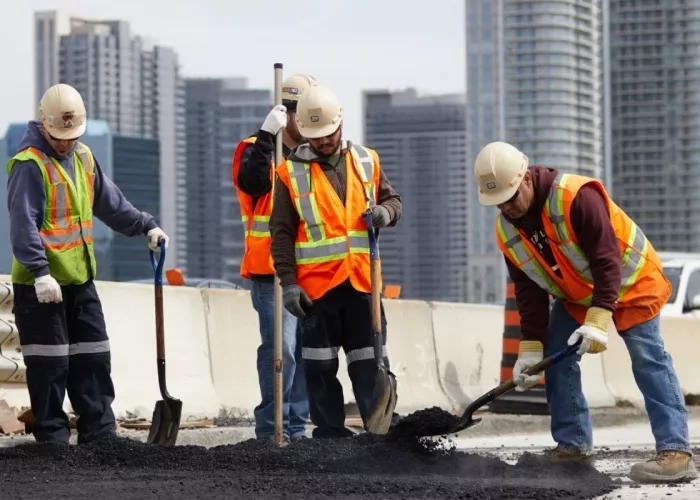 Team members from The Miller Group perform work on the 401 with the Toronto skyline in the background.