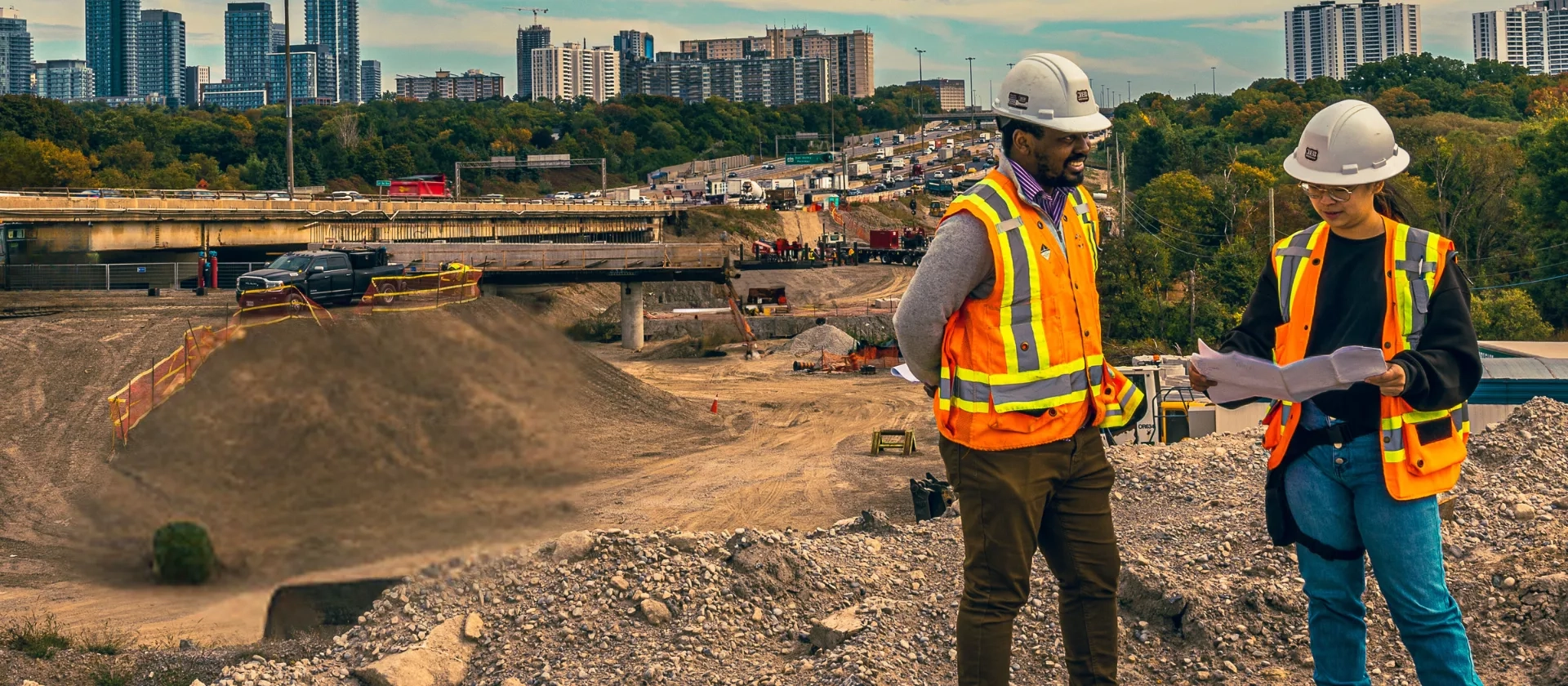 A male and female team member from The Miller Group reviewing documents standing over the Highway 401 Rehabilitation project. 