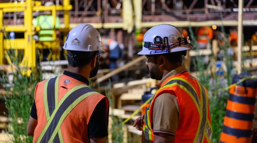 Two construction workers looking over the Leslie Street Bridge being refurbished.