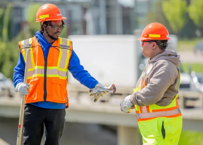 An employee hands his colleague an extra pair of gloves