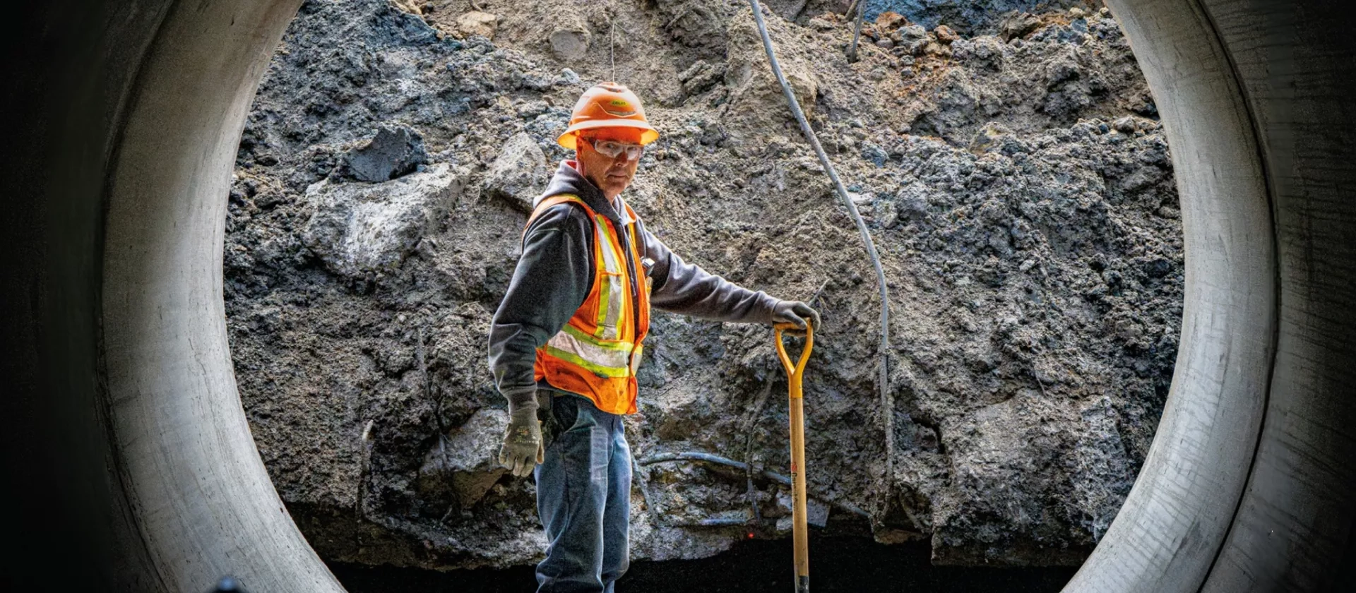 Colas Quebec employee stands inside large pipe while completing an underground works project. 