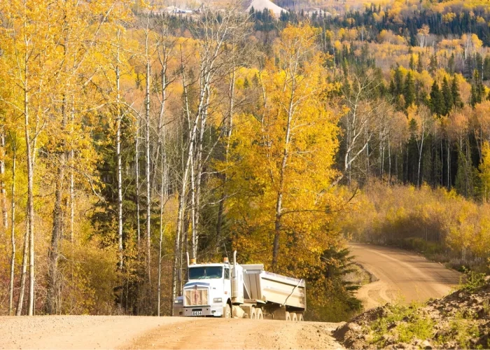 A truck driving along highway 33 with scenic fall colours in the background