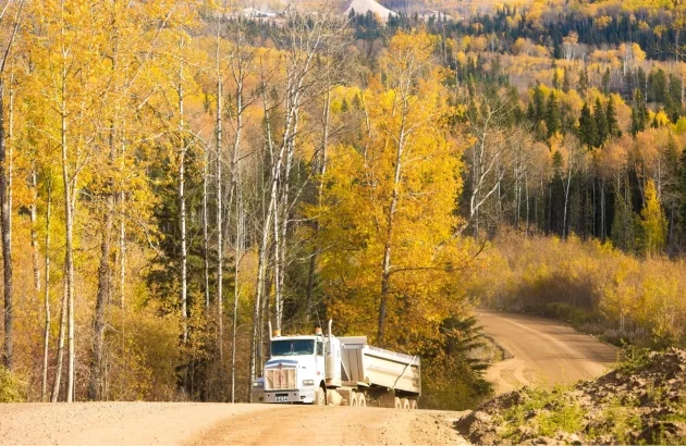 A truck driving along highway 33 with scenic fall colours in the background