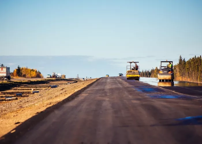 Paving crew completing work on the Highway 33 project with scenic blue sky and forest in the background.
