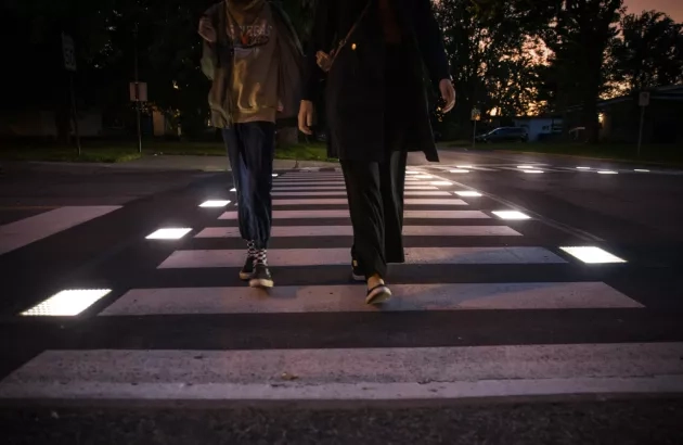 A mother and child walking on the Flowell smart crosswalk as it illuminates in Candiac, Quebec.  