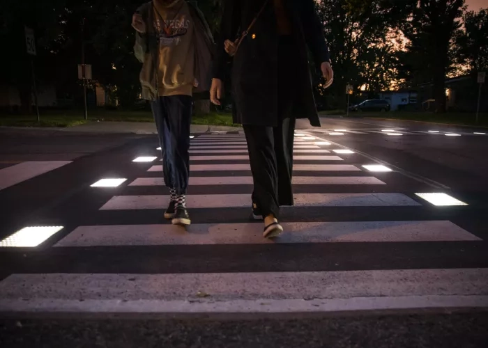 A mother and child walking on the Flowell smart crosswalk as it illuminates in Candiac, Quebec.  