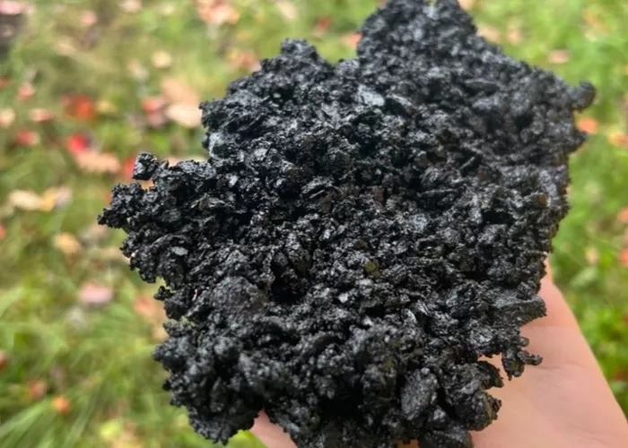 A Colas team member holds a handful of asphalt made from recycled plastic compounds.  