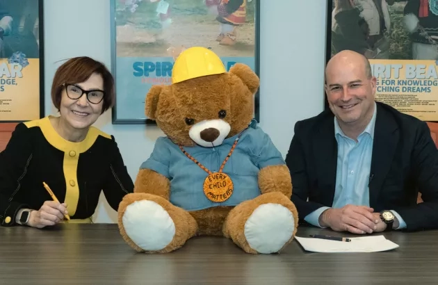 Cindy Blackstock, Gitxsan and Caring Society Executive Director with François Vachon, President and CEO, Colas Canada Inc. seen with Spirit Bear while signing the partnership agreement.