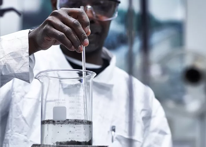 McAsphalt team member takes a sample of liquid for testing.