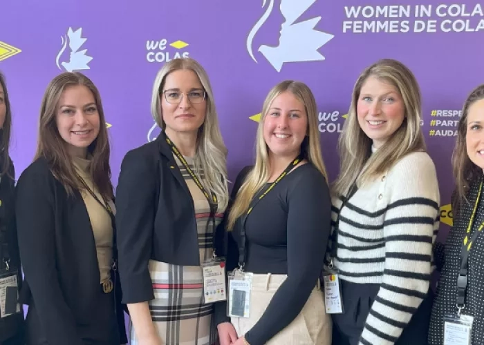 Five women posing for a photo in front of the Women in Colas Conference banner
