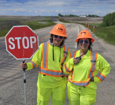 Two road operations employees holding a stop sign to direct traffic