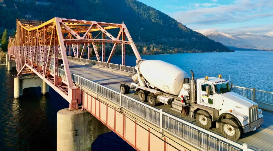 A Terus cement truck drives over a bridge in a natural landscape in British Columbia. 