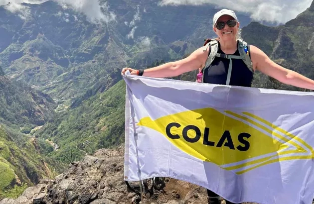 Colas Canada employee Nancy Bastien holds a Colas flag while completing a hike in Madeira, Portugal.  