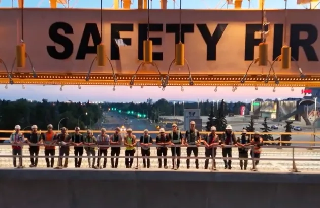 Crews stand in line for a photo on a portion of the elevated guideway with the gantry crane overhead.