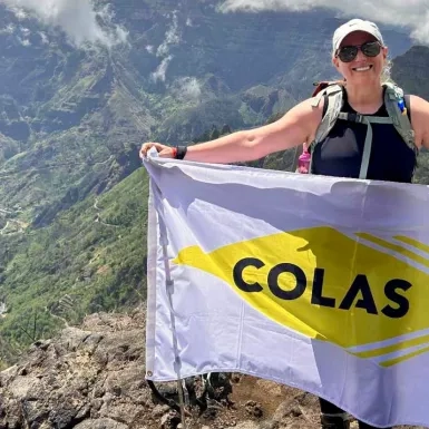 Colas Canada employee Nancy Bastien holds a Colas flag while completing a hike in Madeira, Portugal.  