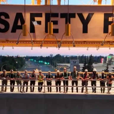 Crews stand in line for a photo on a portion of the elevated guideway with the gantry crane overhead.